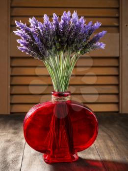 bundle of lavender flowers in red retro vase  on old wooden background