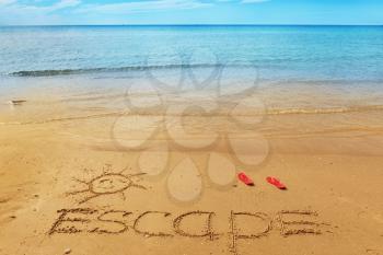 Escape message on the beach sand - vacation and travel concept
