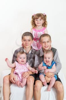 Studio portrait of happy family - brothers and sisters different ages on light background
