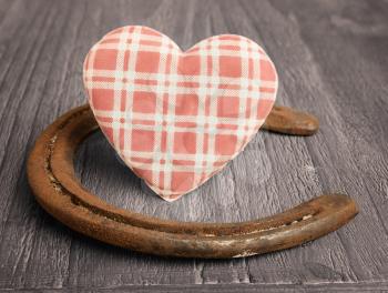
retro fabric heart and old horseshoe on wooden background