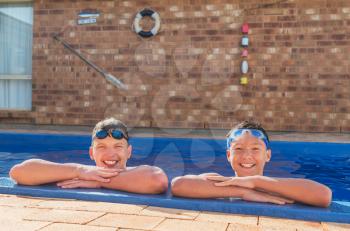 Two young swimmers happy in their private inground pool