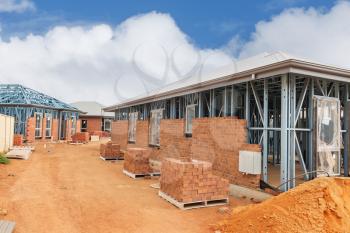 view of construction site with homes from brick with metal framing against a blue sky