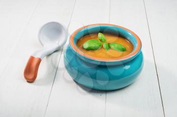 fresh Pumpkin Soup in ceramic bowl with spoon on an old wooden background