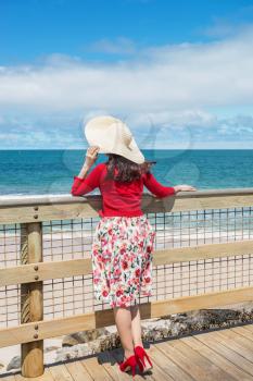 beautiful woman in red standing and looking to the sea 