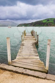 Old wooden pier jetty over the sea shore at Akaroa, New Zealand