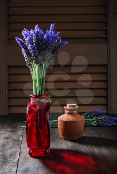 bundle of lavender flowers in retro vase and ceramic pot with oil on old wooden background