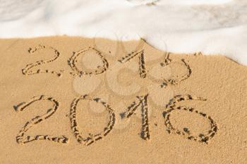 digits  2015 and 2016 on the sand seashore - concept of new year and passing time