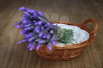 bundle of lavender flowers in wicker basket on vintage wooden table