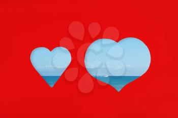 Hearts shaped cut on red paper with sea view through.Love and vacation concept.