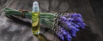 fresh lavender flowers and essential oil as natural aromatherapy for headache and migraine relief on old wooden background