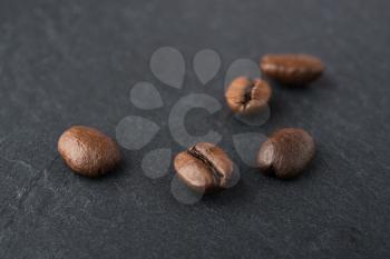 some roasted coffee beans macro shot on a black stone slate plate