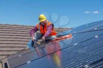 Young worker cleaning solar panels on the roof.Focus on the worker.