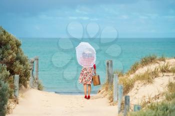 Beautiful woman traveler in retro style dress  on the beach. Local focus on the woman
