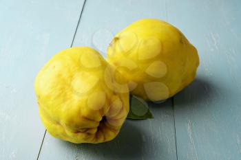 two fresh yellow quinces fruit on rustic wooden table