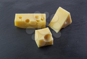 Three pieces of cheese on a black stone slate plate 