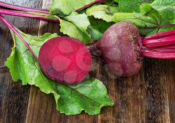  Fresh beetroots with leaves on wet wooden rustic table.Whole and cut  beetroots 