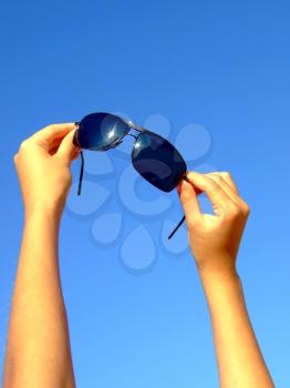 Royalty Free Photo of Female Hands Holding Sunglasses Up to the Sky