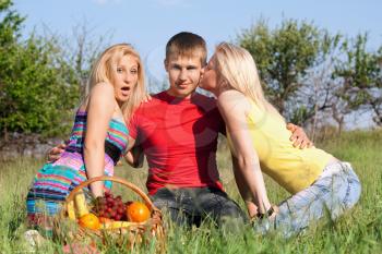 Royalty Free Photo of a Girl Kissing a Boy and Another Girl Looking Surprised