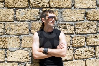 Royalty Free Photo of a Man Wearing Sunglasses Leaning Against a Brick Wall