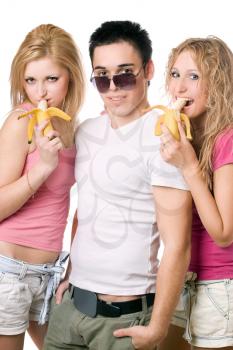 Royalty Free Photo of Two Girls Eating Bananas Standing Beside a Boy