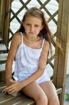 Little girl sitting on a wooden bench