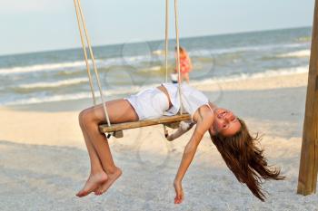 Funny cheerful little girl swinging on a swing