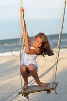 Cheerful little girl swinging on a swing