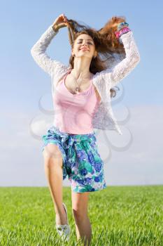Cheerful pretty young woman in a green field