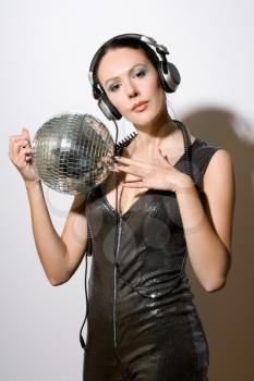 Portrait of sensual young brunette in headphones with a mirror ball