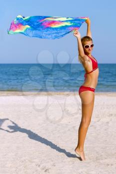 Cute teen girl standing on the beach with pareo in hands