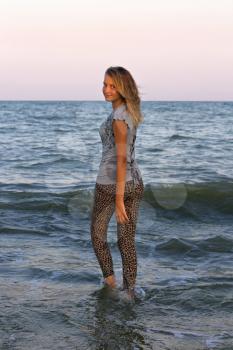 Dressed teen girl walks into the sea