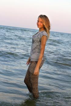Dressed cute teen girl walks into the sea