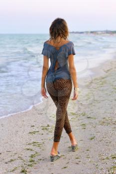 Girl in wet clothes walking on the beach