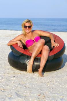 Pretty girl sitting in an inflatable chair on the beach