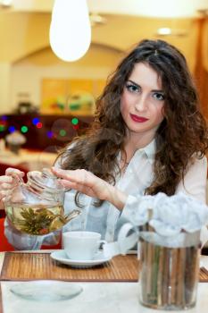 Attractive young woman pours tea into a cup