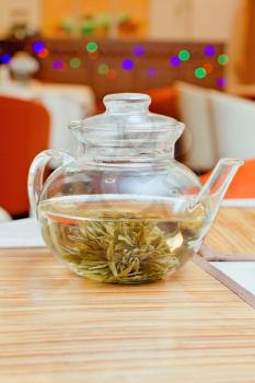 Glass teapot with green tea on a table