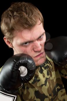 Angry young man in boxing gloves. Isolated on black