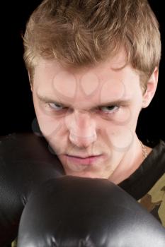 Closeup portrait of angry young man in boxing gloves. Isolated