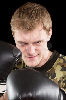 Portrait of grinning angry young man in boxing gloves. Isolated