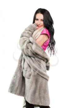 Smiling pretty young brunette in a fur coat. Isolated