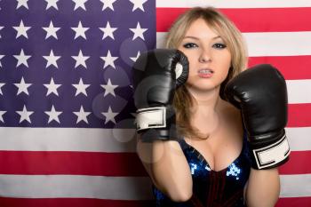 Young blonde with boxing gloves on a background of the American flag