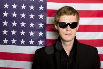 Young man in sunglasses on a background of the American flag