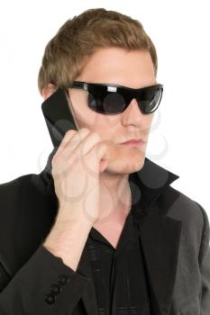 Young businessman in black talking on the mobile phone. Isolated