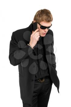 Man wearing black suit and shirt talking on the mobile phone. Isolated
