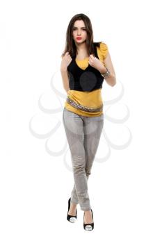 Seductive brunette wearing grey jeans, yellow t-short and black vest. Isolated on white