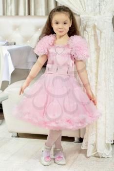 Beautiful little girl in lace pink dress posing indoors