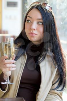 Attractive young woman with a glass of champagne looking away. Isolated on white