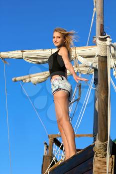 Beautiful teen girl standing at stern of the ship