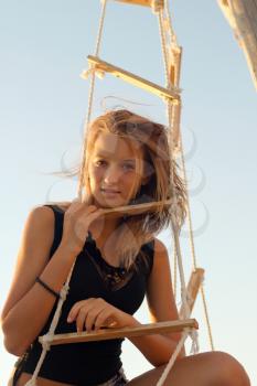 Lovely teen girl sitting at stern of the ship