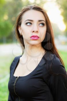 Young thoughtful woman wearing black dress posing outdoor